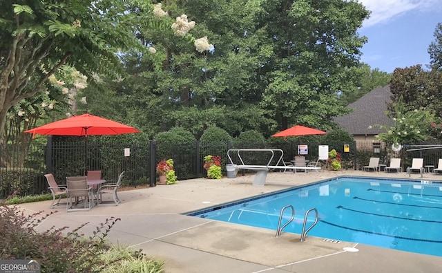 pool with a patio area and fence