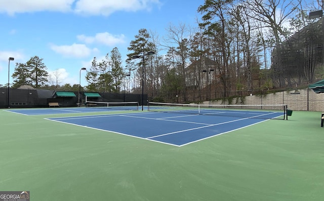 view of tennis court featuring community basketball court and fence