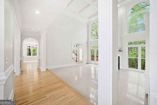 interior space featuring crown molding, decorative columns, and a towering ceiling