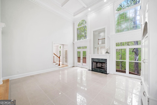 unfurnished living room featuring tile patterned floors, a high ceiling, a wealth of natural light, and stairs