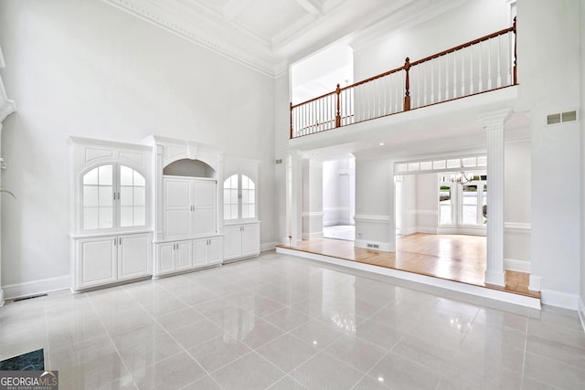 unfurnished living room with decorative columns, a towering ceiling, visible vents, and light tile patterned floors
