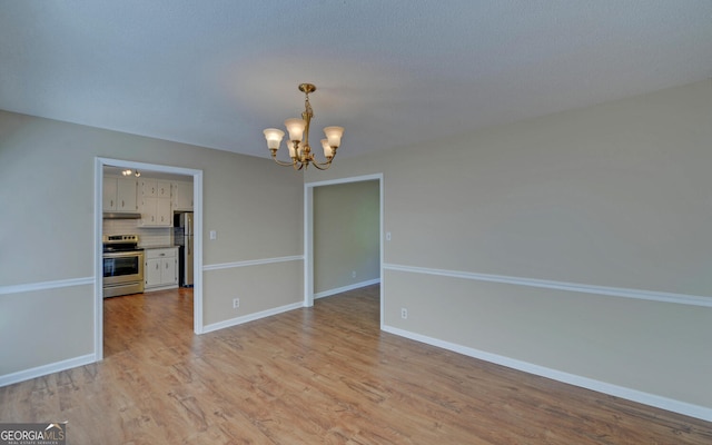 186 Foxdale Dr, Toccoa, GA 30577 - spare room featuring baseboards, a chandelier, and light wood-style flooring