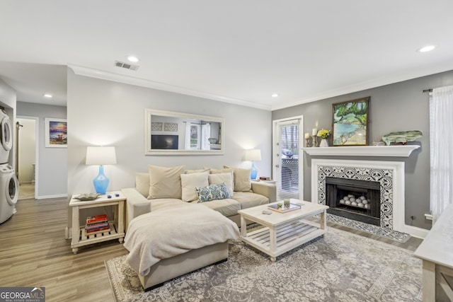 living room featuring recessed lighting, visible vents, stacked washer and dryer, and wood finished floors