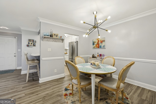 dining space featuring light wood-style flooring, crown molding, a notable chandelier, and baseboards
