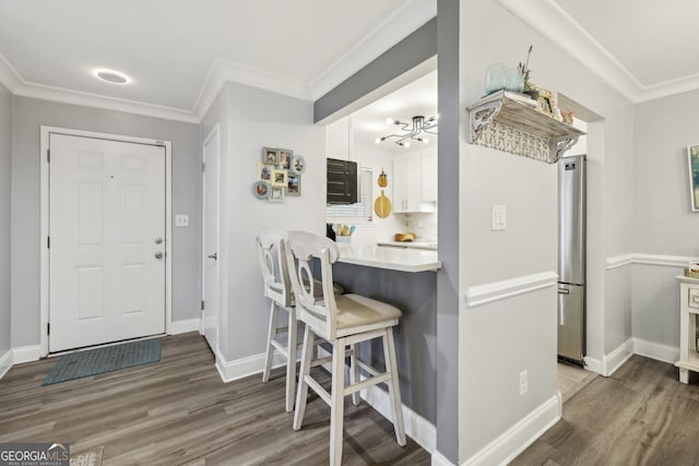 kitchen with freestanding refrigerator, crown molding, and wood finished floors