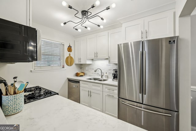 kitchen featuring a sink, decorative backsplash, appliances with stainless steel finishes, and white cabinetry