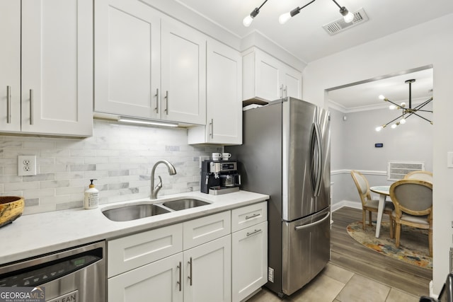 kitchen with tasteful backsplash, white cabinets, visible vents, appliances with stainless steel finishes, and a sink