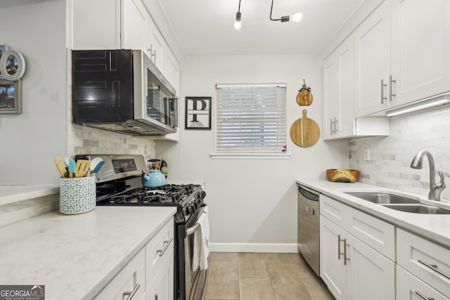 kitchen featuring stainless steel appliances, white cabinetry, a sink, and decorative backsplash