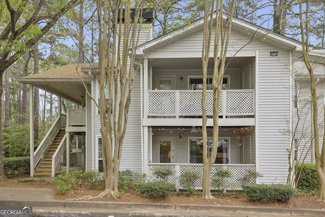 view of front of property featuring a chimney, a porch, stairway, and a balcony