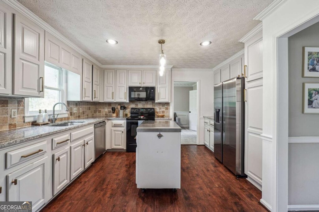kitchen with a center island, black appliances, backsplash, and a sink