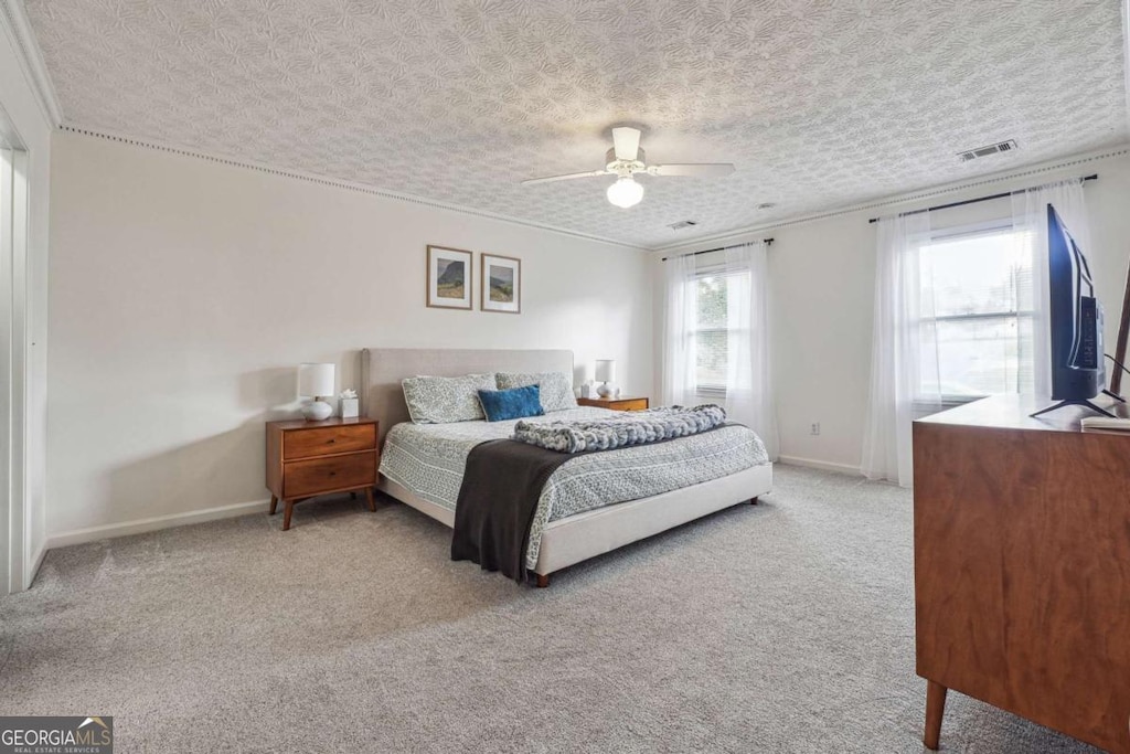bedroom with crown molding, a ceiling fan, visible vents, baseboards, and carpet floors
