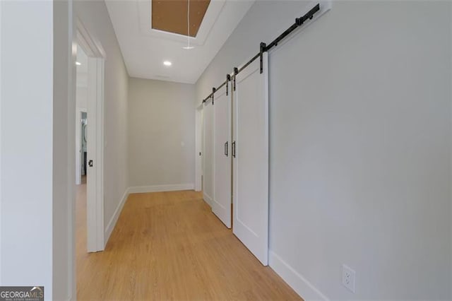 hall with recessed lighting, a barn door, light wood-type flooring, and baseboards