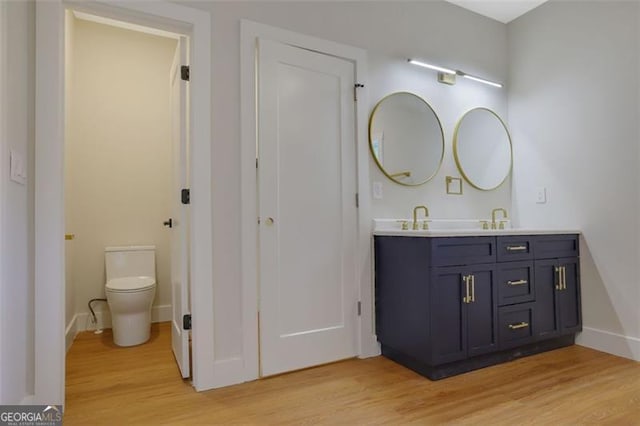 full bathroom featuring a sink, toilet, double vanity, and wood finished floors