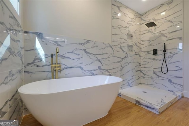 bathroom featuring a soaking tub, tile walls, a marble finish shower, and wood finished floors