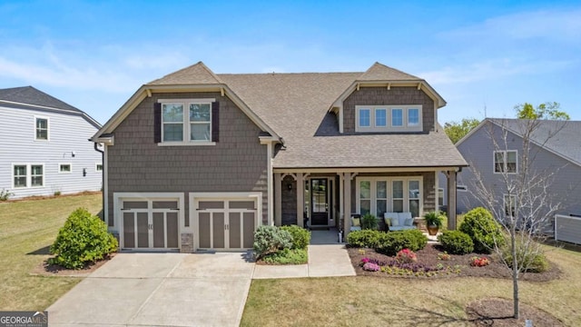 craftsman-style house featuring driveway, an attached garage, a shingled roof, a front yard, and a porch