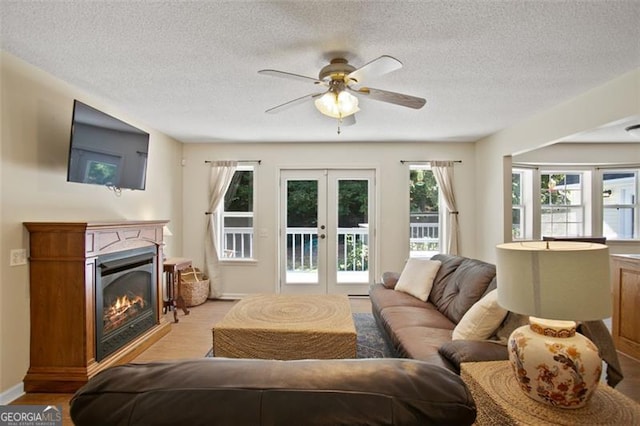 19 Mccrary Ct, Ellijay, GA 30536 - living area featuring a glass covered fireplace, french doors, a textured ceiling, ceiling fan, and light wood finished floors