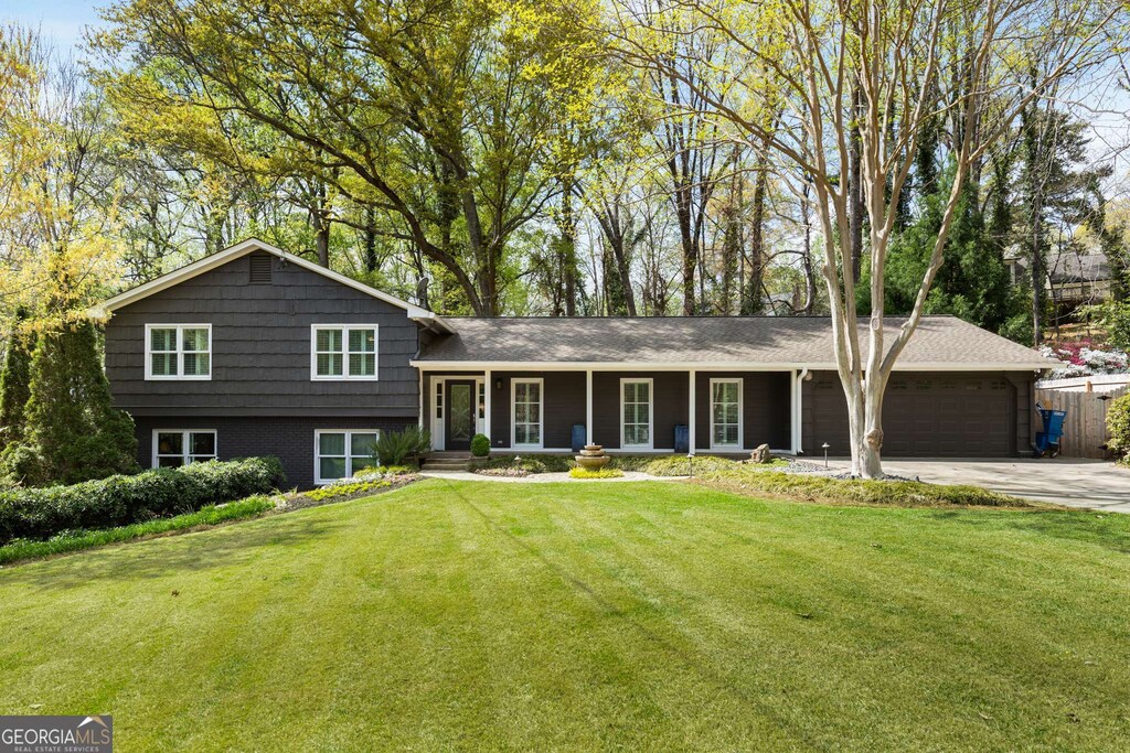 tri-level home featuring driveway, a front lawn, and an attached garage