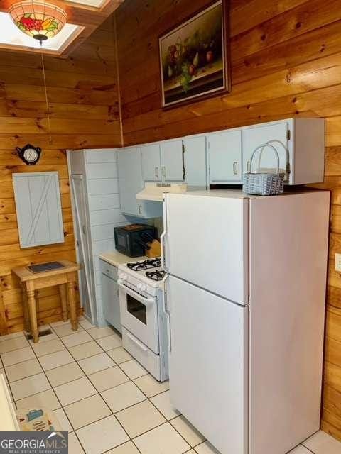 2209 Bell View Ln, Young Harris, GA 30582 - kitchen with light countertops, wooden walls, light tile patterned floors, and white appliances