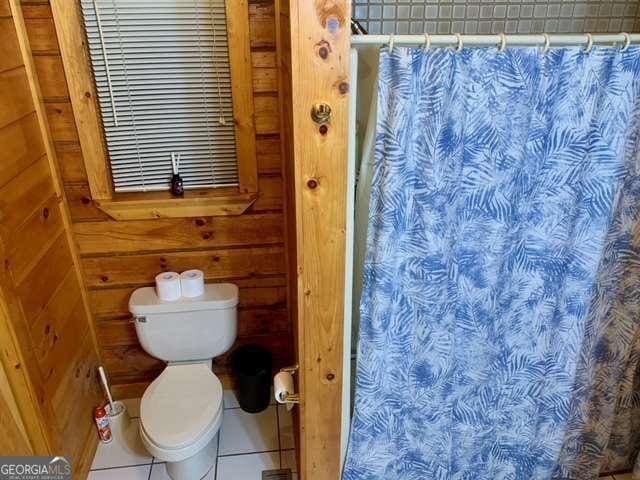 2209 Bell View Ln, Young Harris, GA 30582 - bathroom with tile patterned flooring, wooden walls, toilet, and a shower with curtain