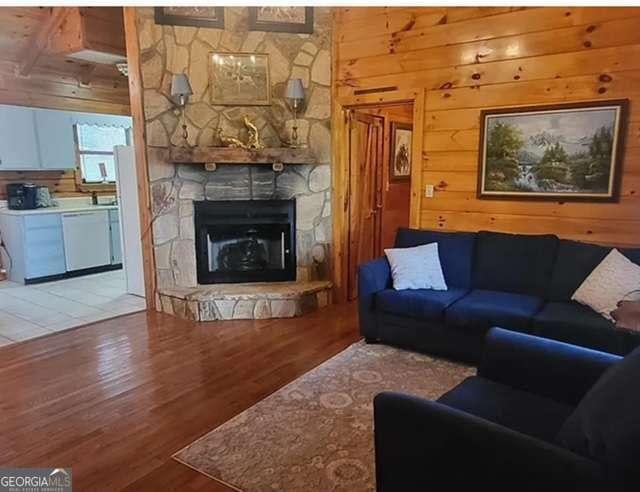 2209 Bell View Ln, Young Harris, GA 30582 - living room featuring wooden walls, wood finished floors, and a stone fireplace
