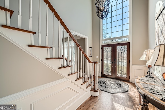 foyer with french doors, wood finished floors, a towering ceiling, and stairs