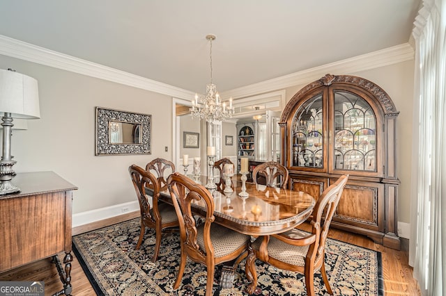 dining room with ornamental molding, baseboards, a chandelier, and wood finished floors