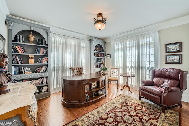 office with built in shelves, crown molding, and wood finished floors