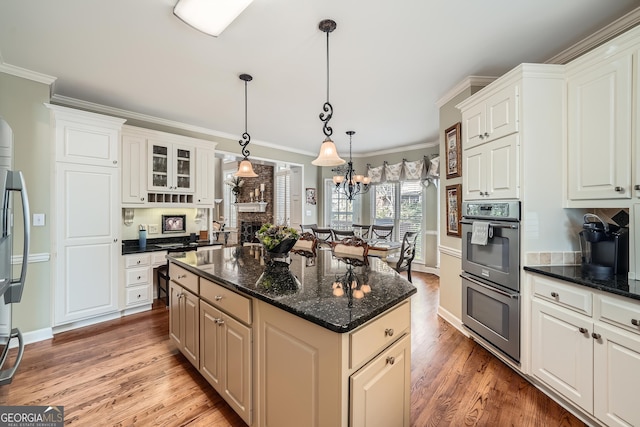 kitchen with light wood-style floors, double oven, crown molding, and a kitchen island