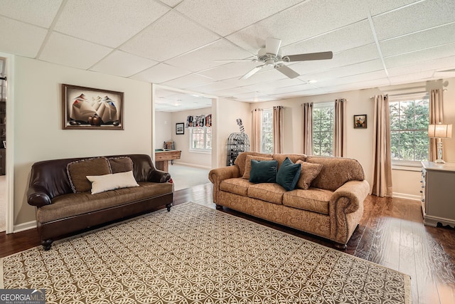 living room with dark wood finished floors, a paneled ceiling, baseboards, and ceiling fan