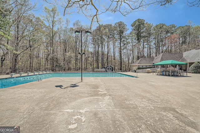 community pool with a patio area and fence