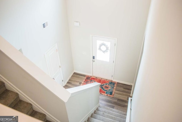 entryway featuring visible vents, a towering ceiling, wood finished floors, and stairway