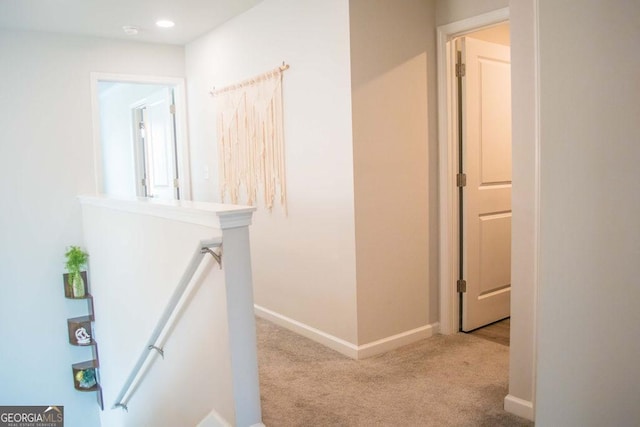 hallway with recessed lighting, baseboards, an upstairs landing, and carpet