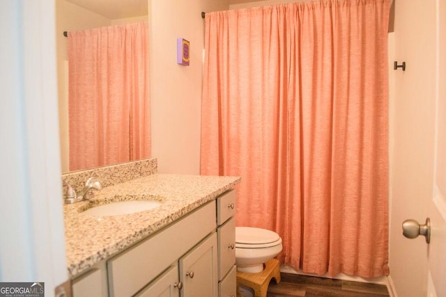 bathroom featuring toilet, vanity, wood finished floors, and curtained shower
