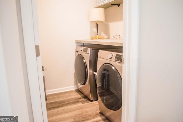 clothes washing area featuring light wood-style floors, baseboards, washer and clothes dryer, and laundry area