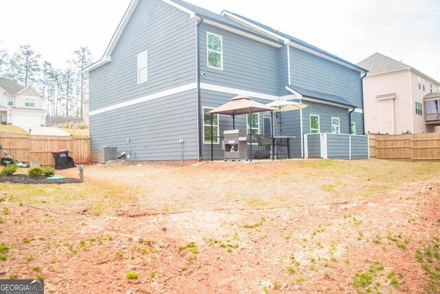 rear view of house with central air condition unit, fence, and a gazebo