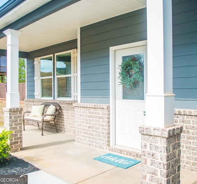 view of exterior entry with covered porch and brick siding