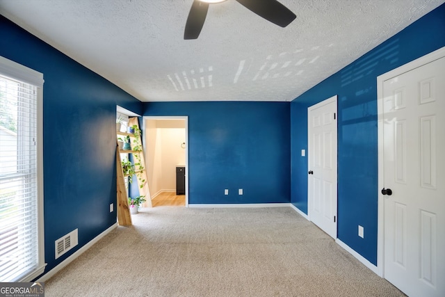 unfurnished bedroom featuring a textured ceiling, visible vents, baseboards, and carpet