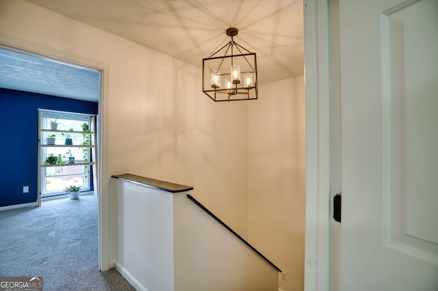 stairs featuring baseboards, an inviting chandelier, and carpet
