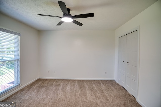 unfurnished bedroom with carpet floors, baseboards, a closet, and ceiling fan