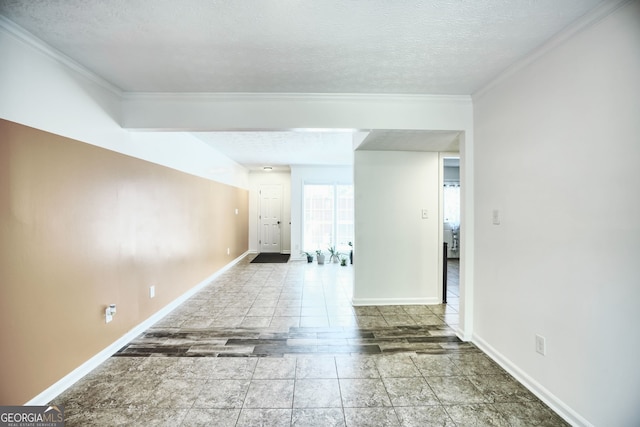 spare room with baseboards, ornamental molding, and a textured ceiling
