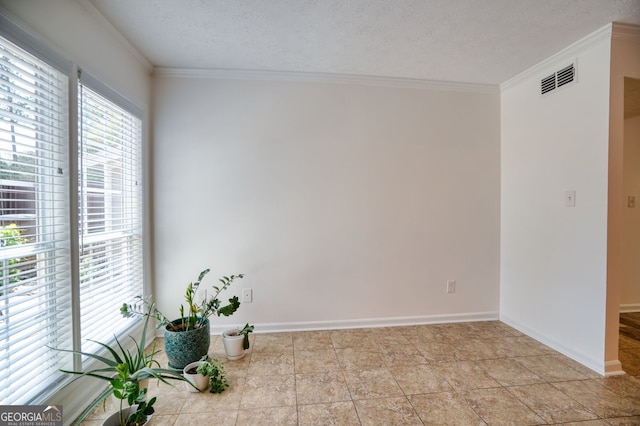 empty room featuring crown molding, baseboards, a textured ceiling, and visible vents