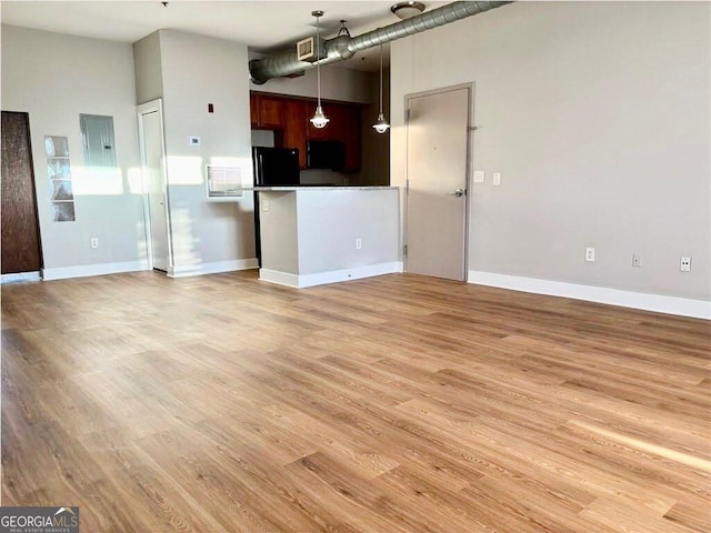 unfurnished living room with light wood-style flooring, baseboards, and visible vents