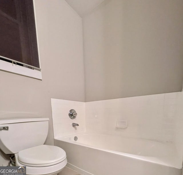 bathroom with a bath, toilet, tile patterned flooring, and vaulted ceiling