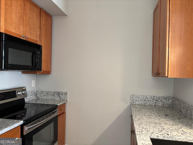 kitchen featuring black microwave, stainless steel electric range oven, and brown cabinetry