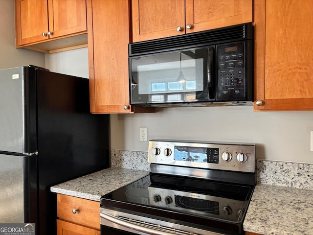 kitchen with light stone countertops, brown cabinets, and black appliances