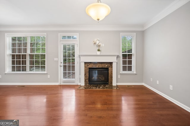 unfurnished living room featuring baseboards, ornamental molding, a fireplace, visible vents, and wood finished floors