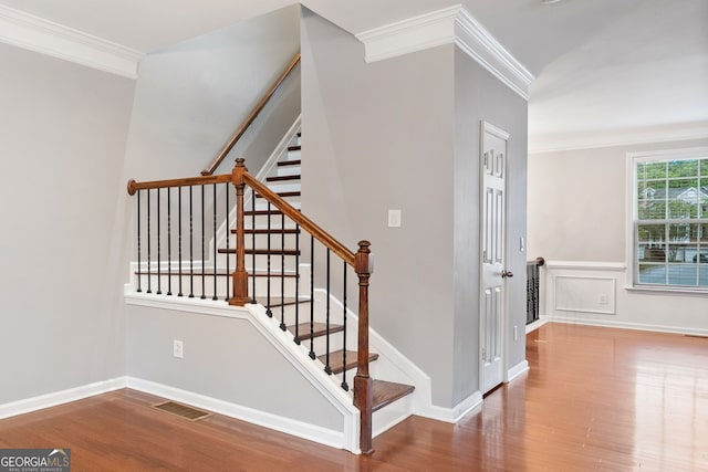 staircase featuring visible vents, baseboards, ornamental molding, and wood finished floors