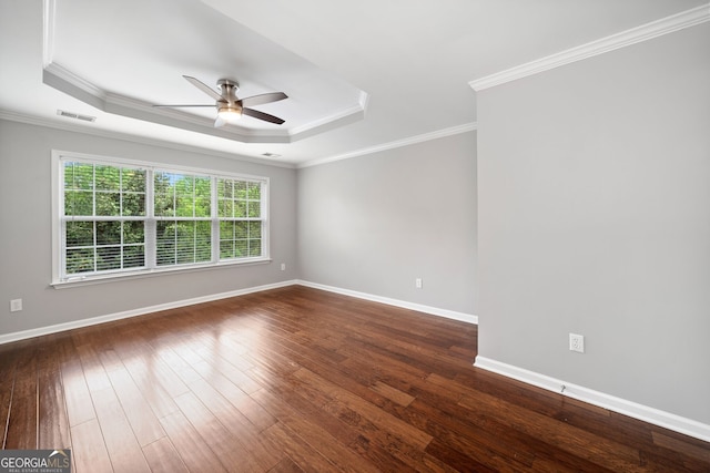 empty room featuring dark wood-type flooring, visible vents, ceiling fan, and a raised ceiling