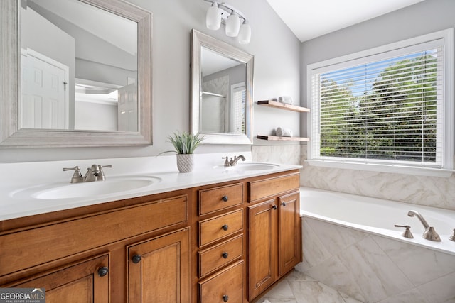 bathroom with a bath, a shower with shower door, double vanity, and a sink
