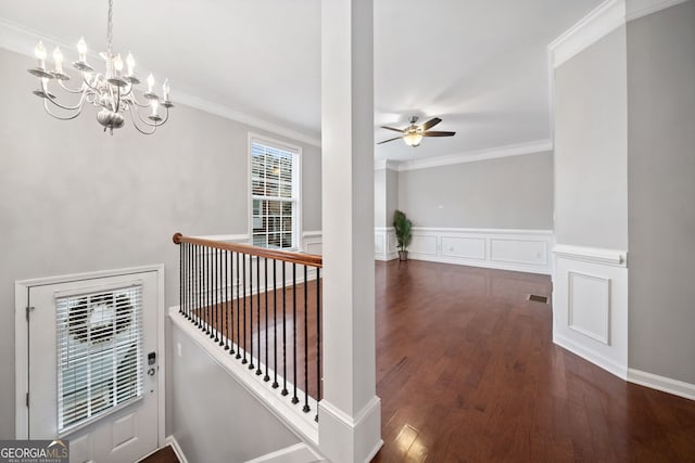 hallway featuring crown molding, an inviting chandelier, visible vents, wood finished floors, and an upstairs landing